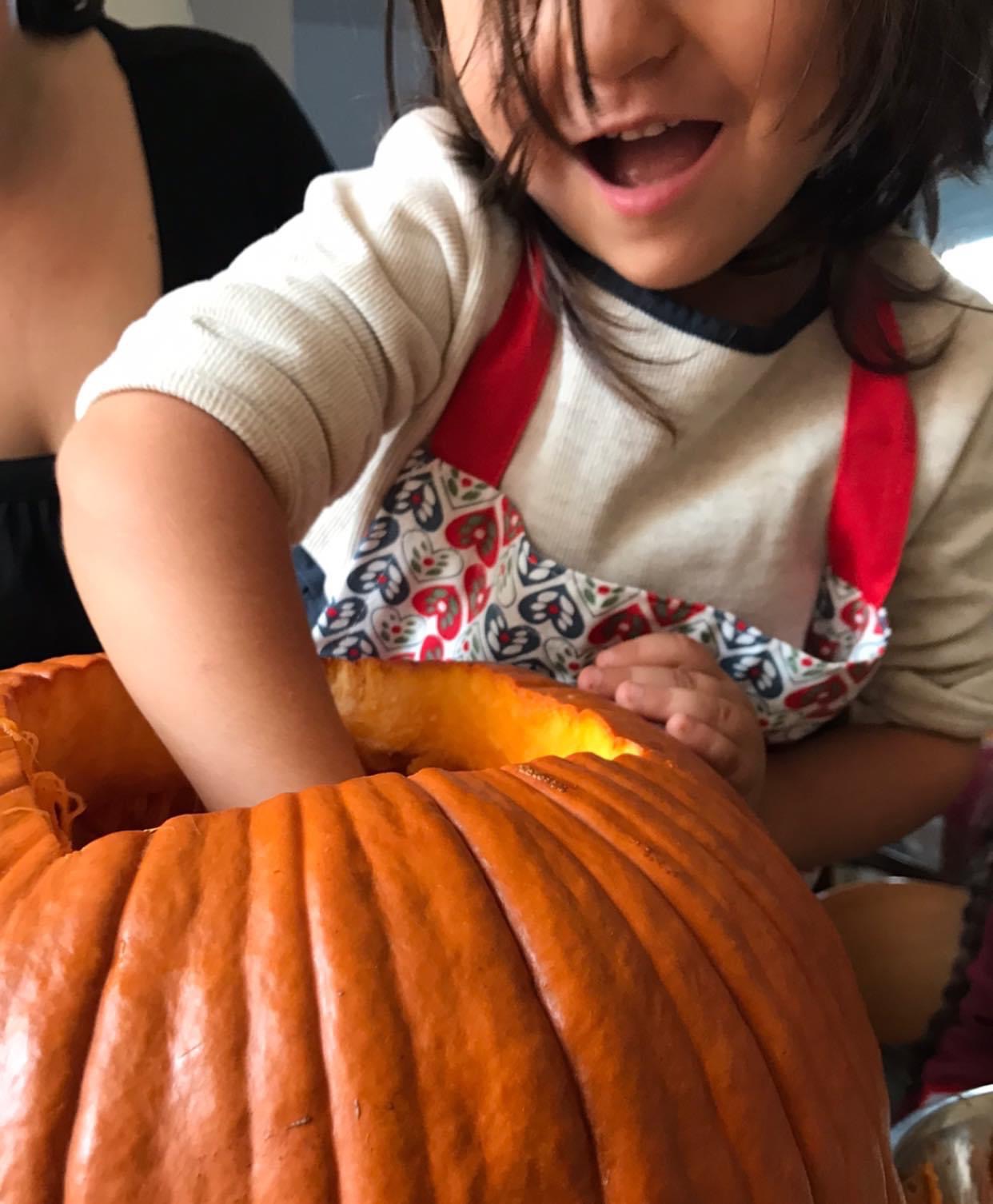 Una bambina infila la mano in una zucca di Halloween