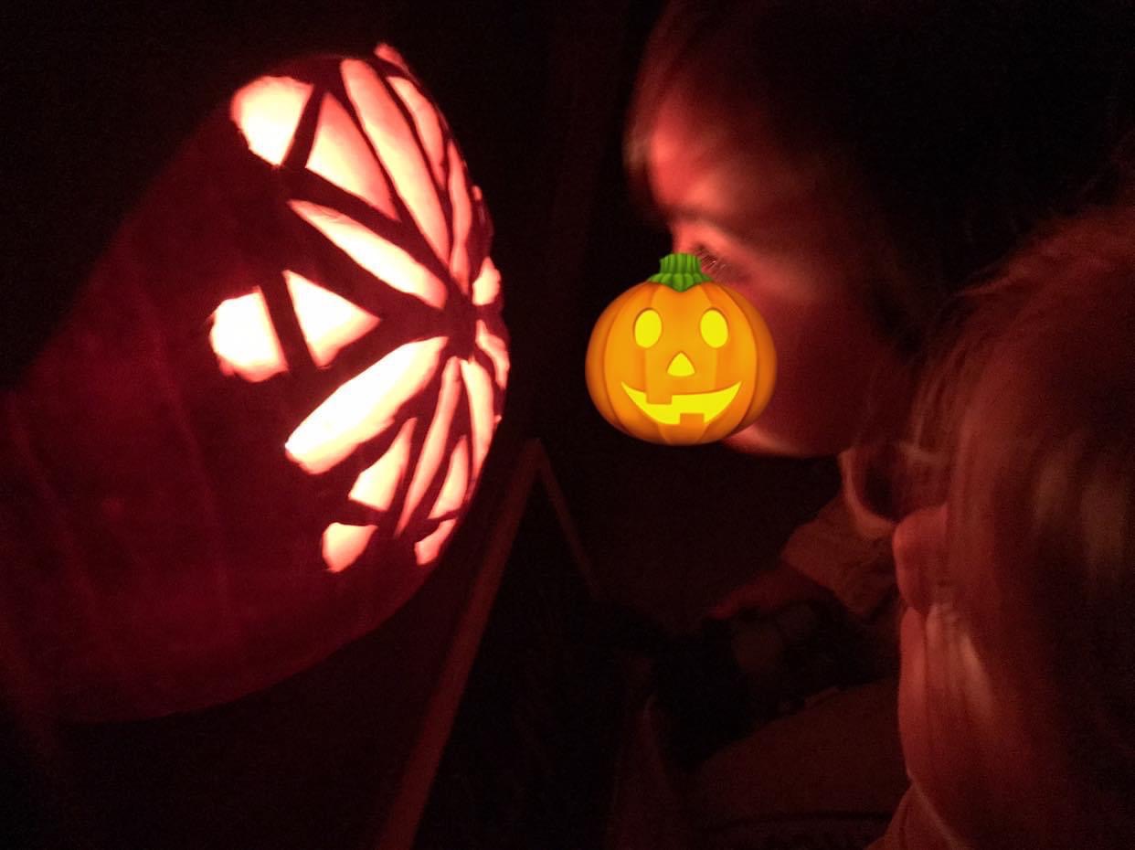 Un bambino che guarda dentro una zucca-lanterna di Halloween